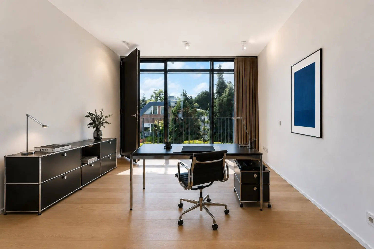 Modernes Arbeitszimmer mit Schreibtisch, Stuhl und großem Fenster mit Blick nach draußen.