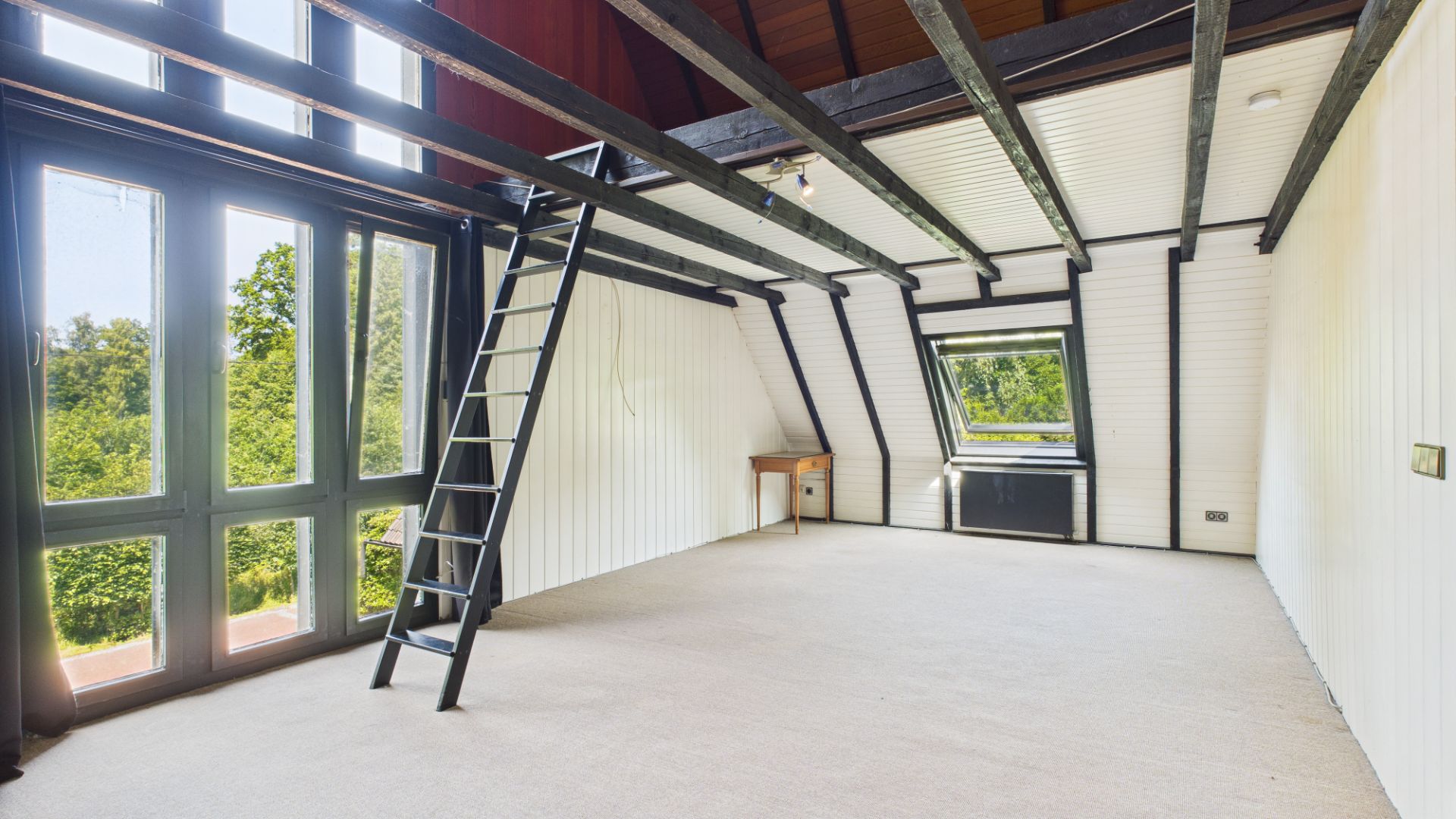 Helles Zimmer mit Galerie, Leiter, großen Fenstern und Schreibtisch, Blick ins Grüne.