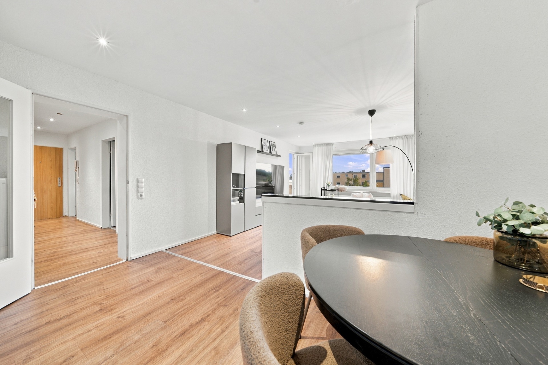 Helles Wohnzimmer mit offenem Essbereich, Holzboden und modernen Möbeln.