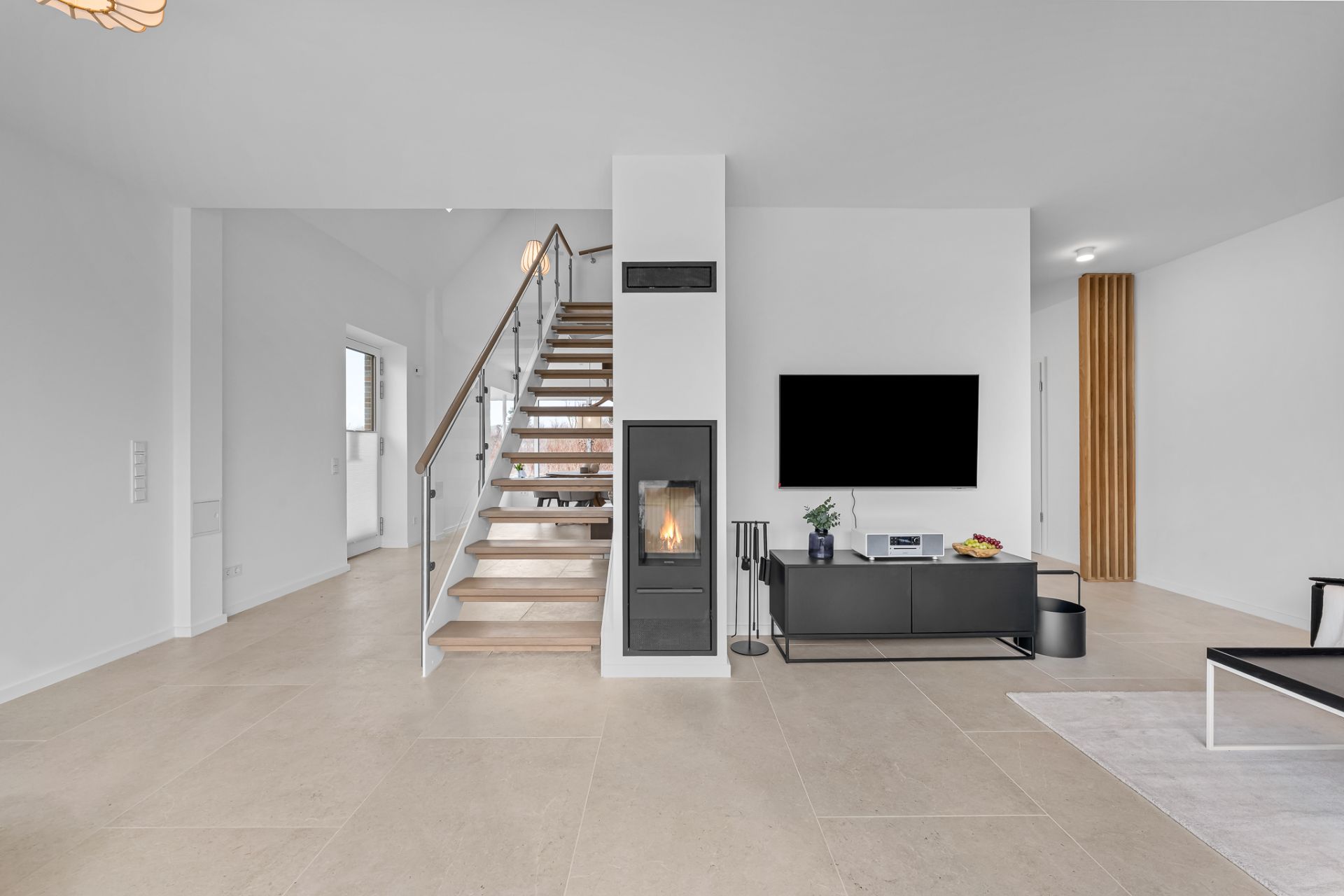 Modernes Wohnzimmer mit Kamin, TV, Treppe und schlichten Möbeln.