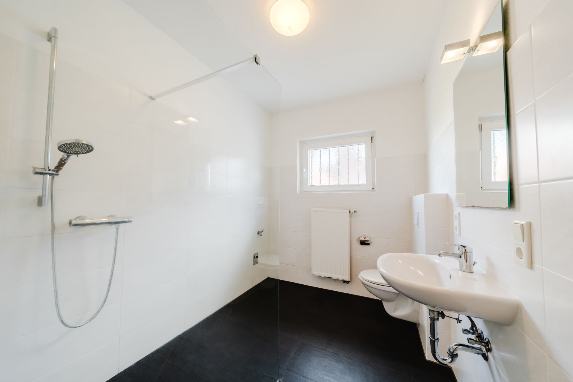 Modernes, barrierefreies Badezimmer mit offener Dusche, Waschbecken und Fenster.