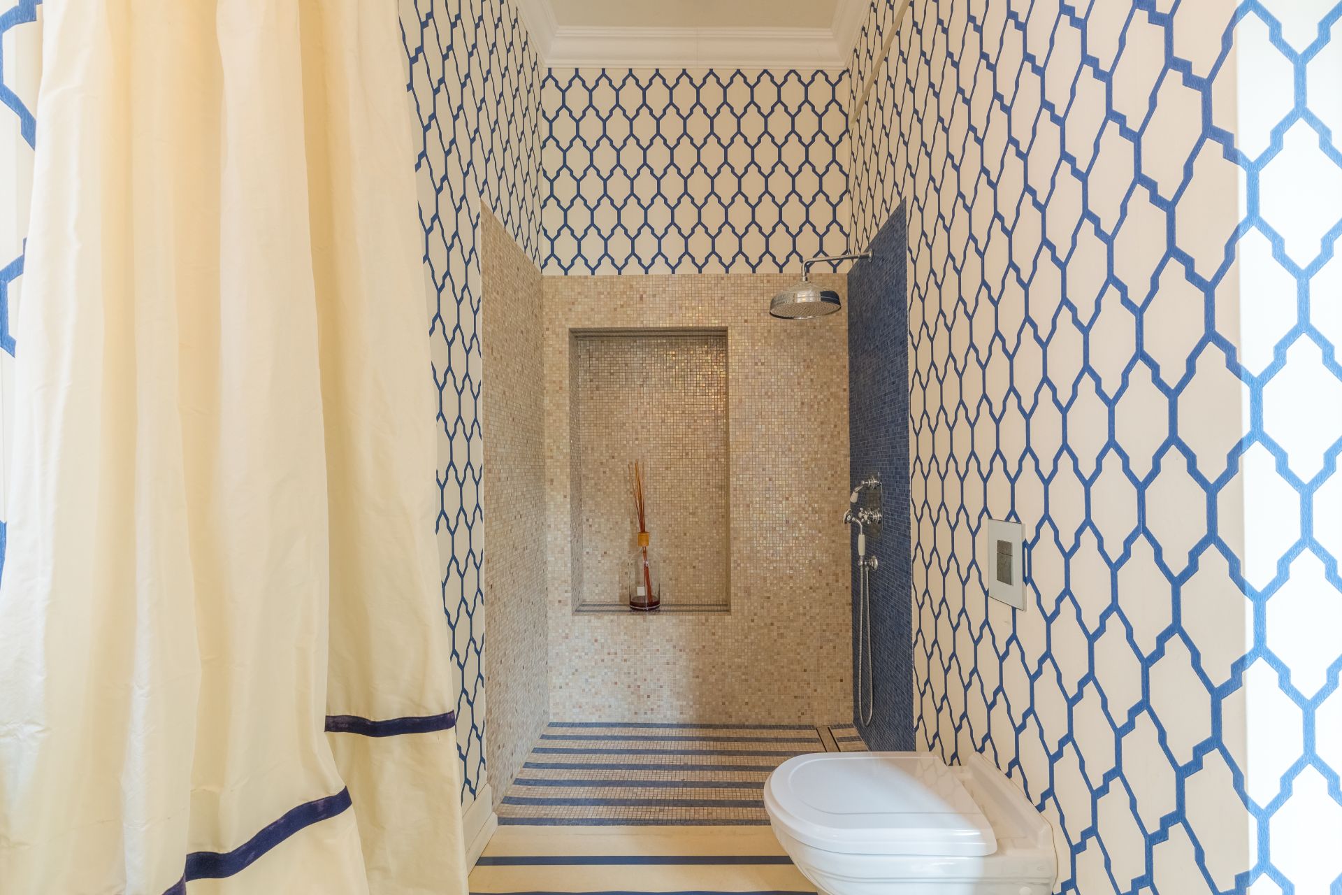 Badezimmer mit gemusterten Wänden, Dusche und Wandtoilette.