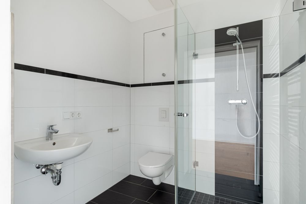 Modernes Badezimmer mit Waschbecken, Wandtoilette und Glasdusche.