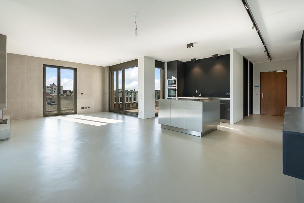 Helle, moderne offene Küche mit Kochinsel und großen Fenstern zum Balkon.