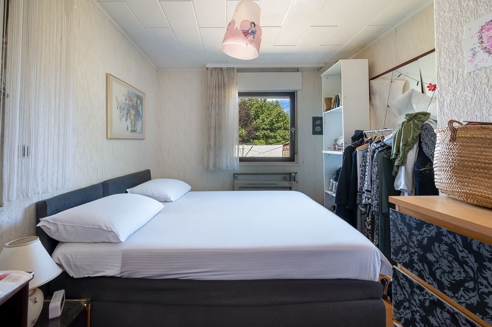 Schlafzimmer mit Doppelbett, Fenster, Kleiderschrank und Kommode, hell und ordentlich eingerichtet.