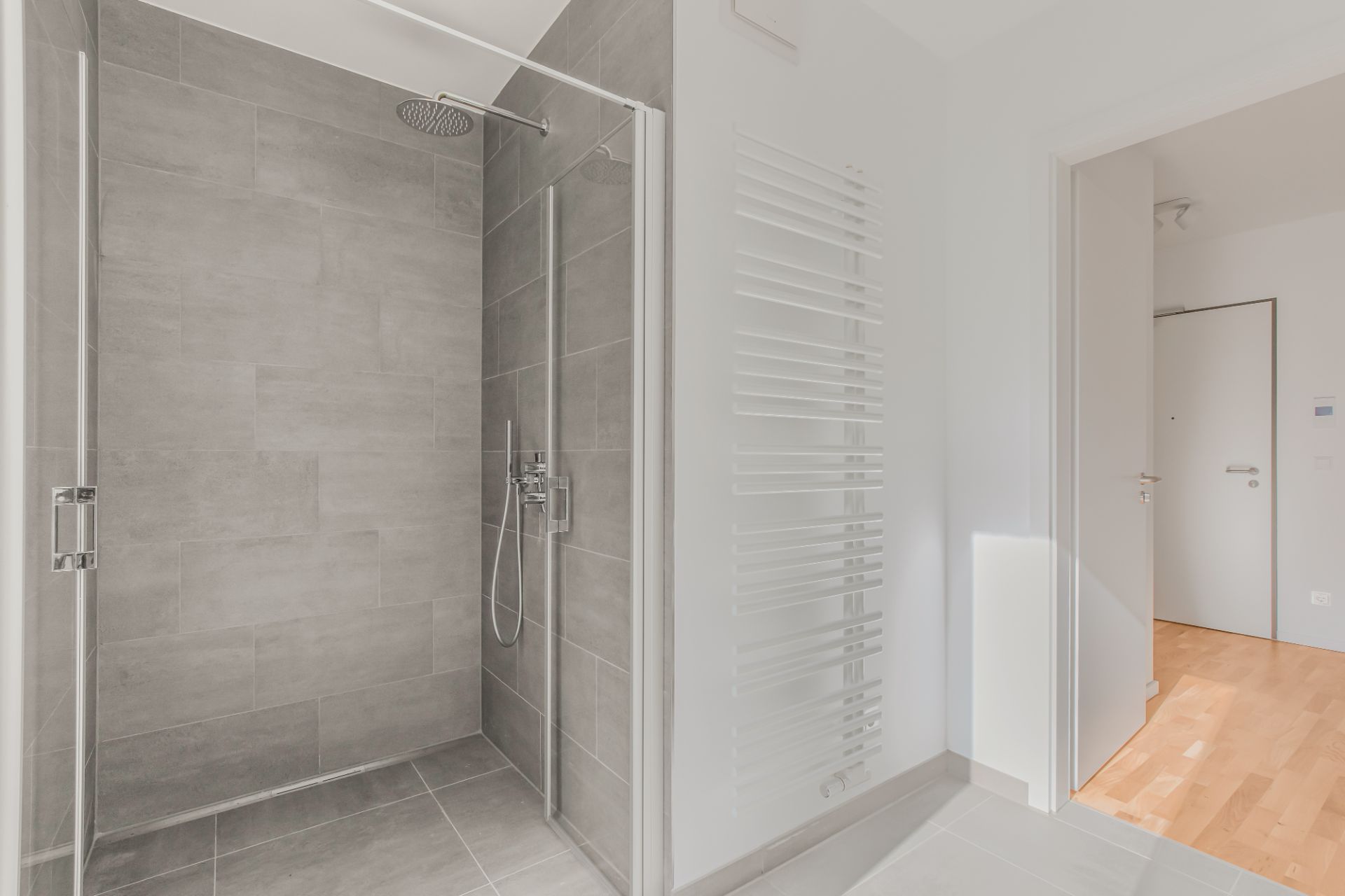 Modernes Badezimmer mit großer, ebenerdiger Dusche und Handtuchheizkörper.