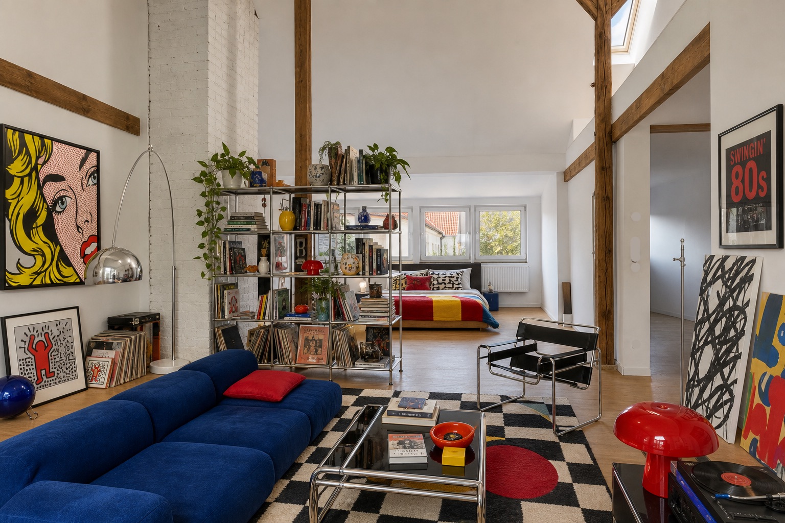 Modernes Wohnzimmer mit blauem Sofa, bunten Pop-Art-Bildern und Blick auf ein Schlafzimmer.