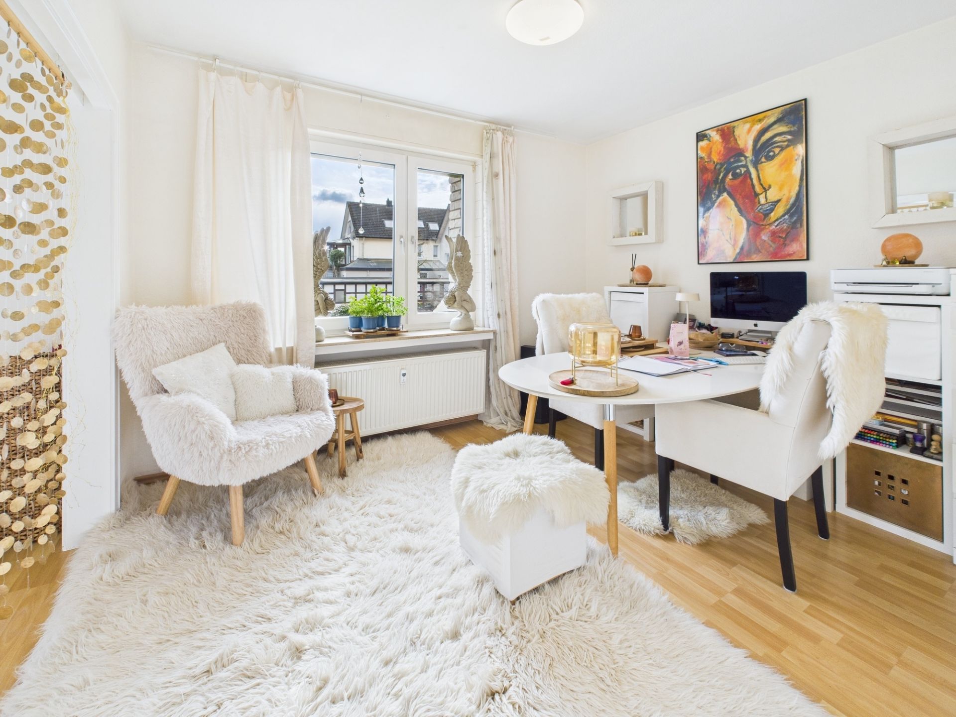 Helles Arbeitszimmer mit Schreibtisch, Stühlen, Teppich und buntem Gemälde an der Wand.