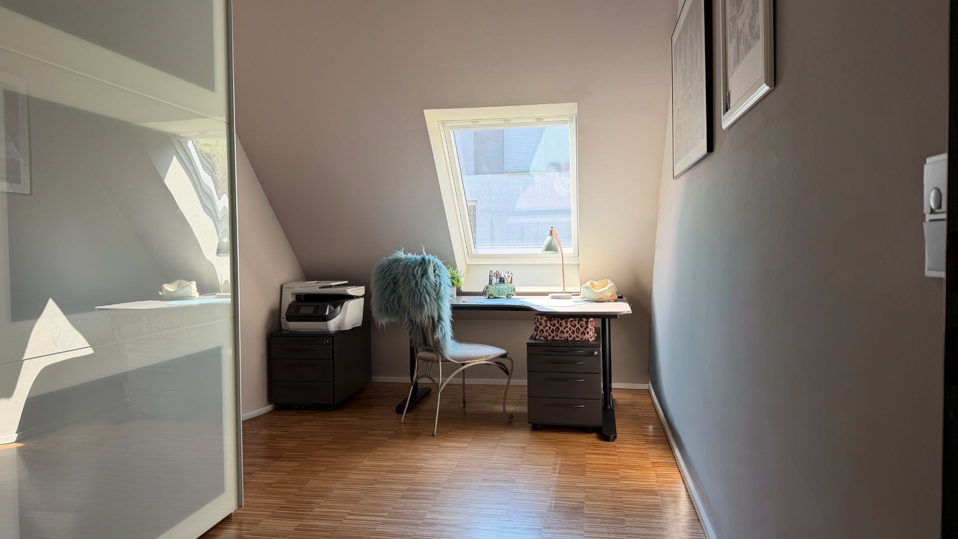Helles Arbeitszimmer mit Schreibtisch, Stuhl und Dachfenster auf Holzfußboden.