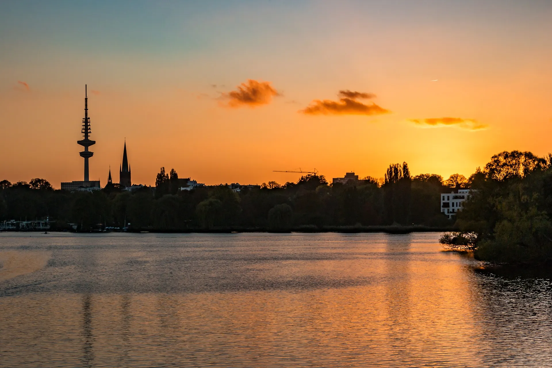 See mit Gebäuden und Bäumen im Sonnenuntergang, Himmel orange gefärbt.