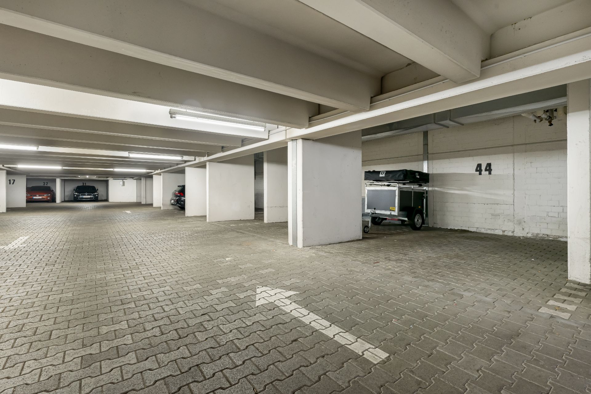 Tiefgaragenstellplätze mit mehreren Autos und Stellplatznummern an den Wänden.