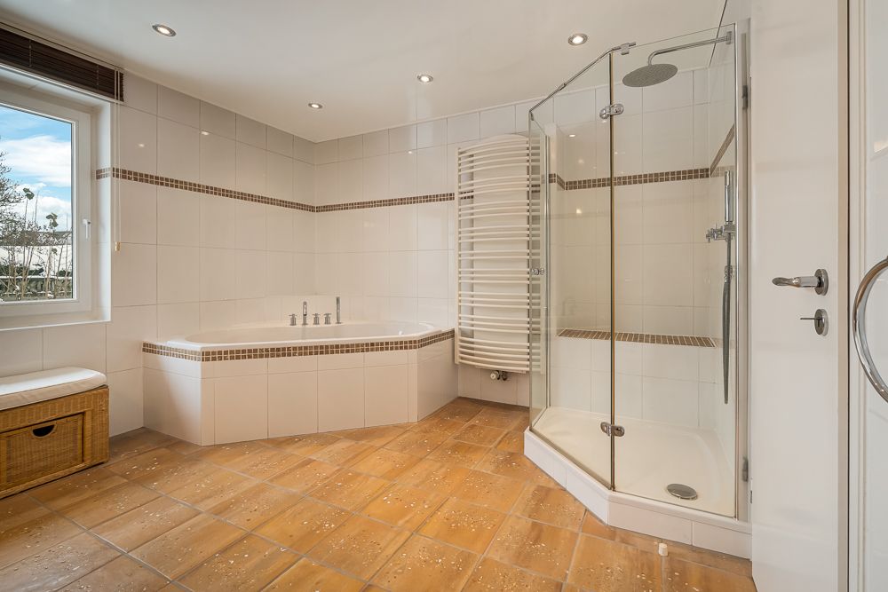 Modernes Badezimmer mit Eckbadewanne, Dusche, Fenster und Handtuchheizkörper.