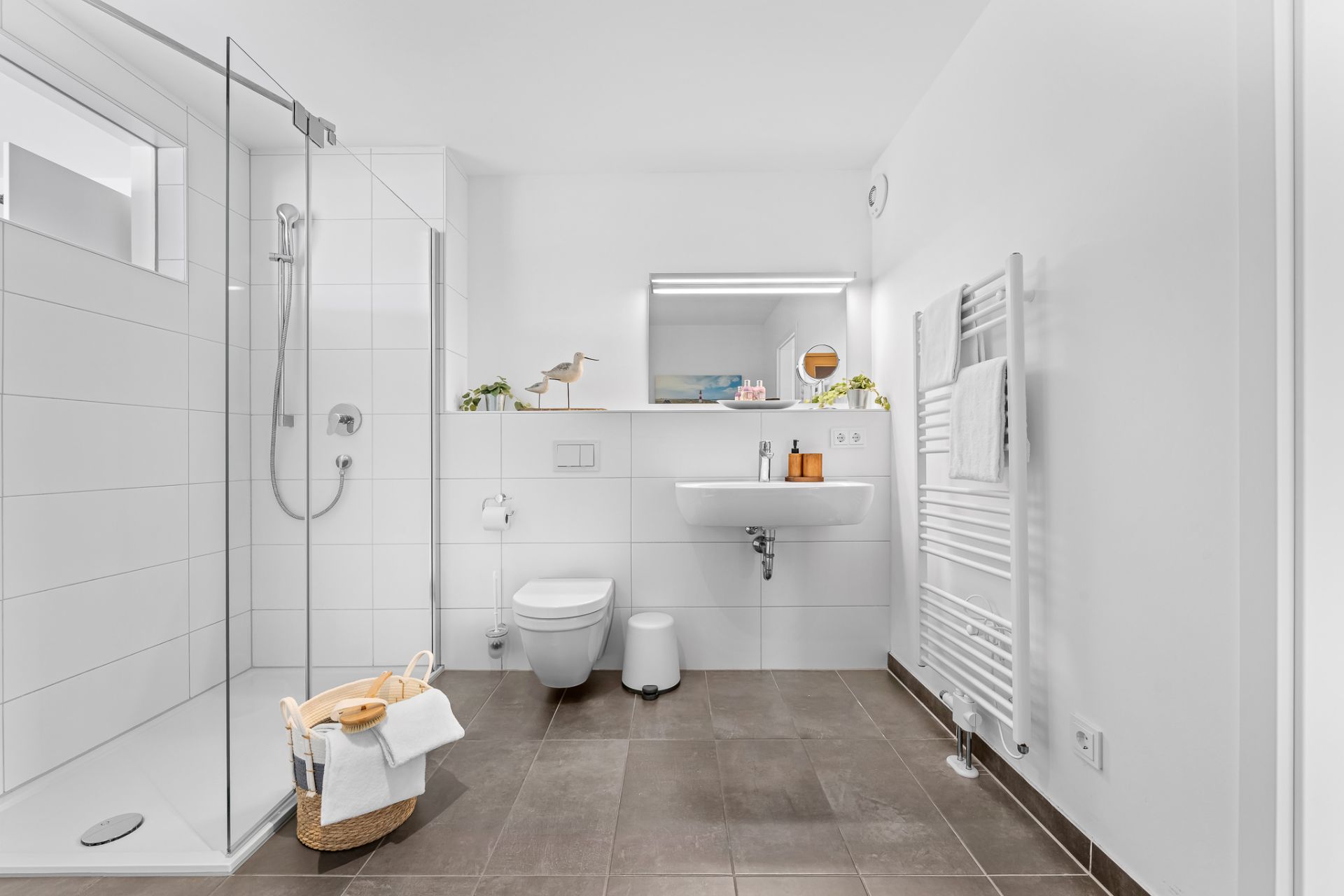 Modernes Badezimmer mit Dusche, WC, Waschbecken und Handtuchheizkörper.