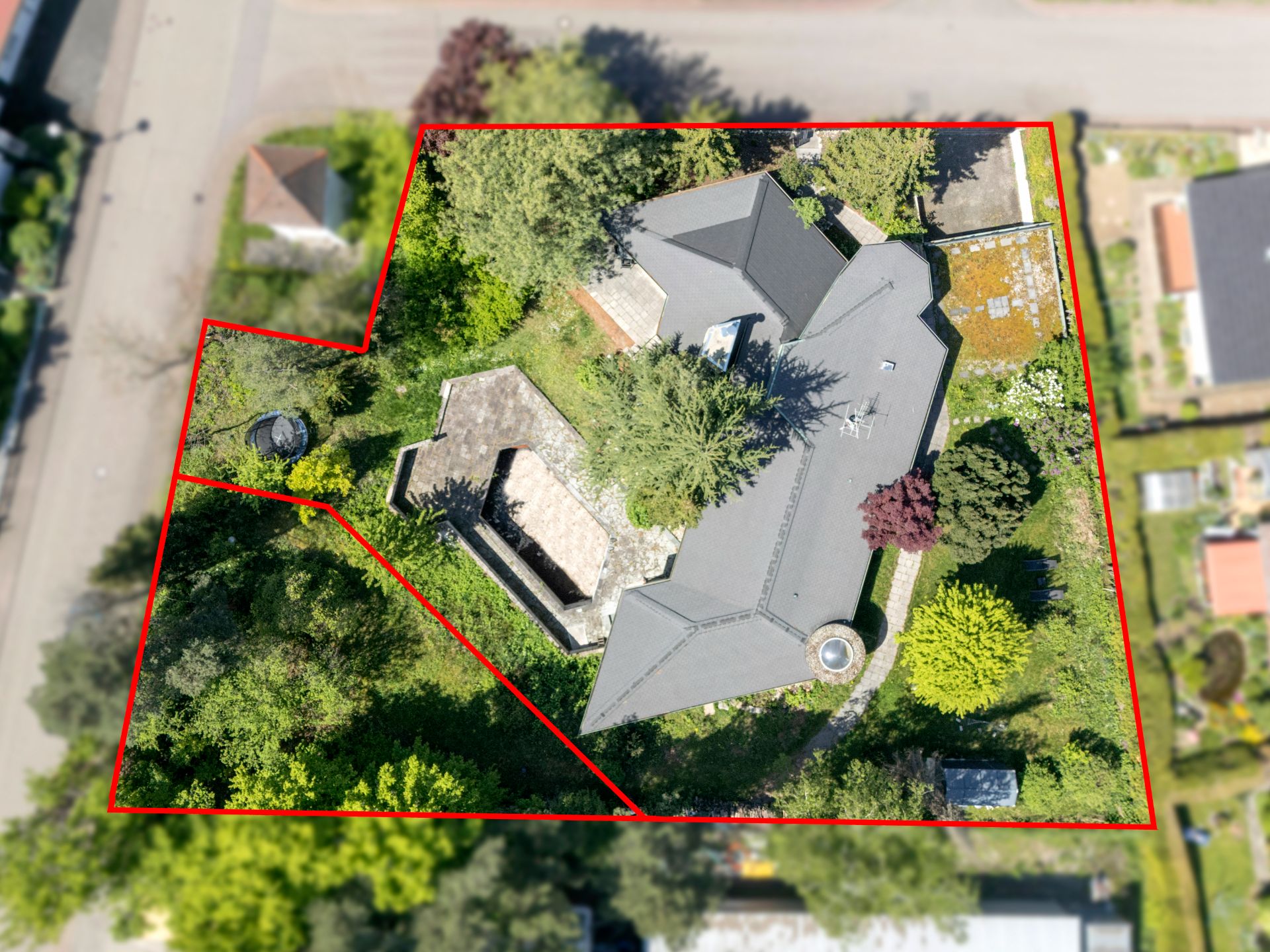 Luftaufnahme eines Grundstücks mit Haus und Garten, durch eine rote Linie umrandet.