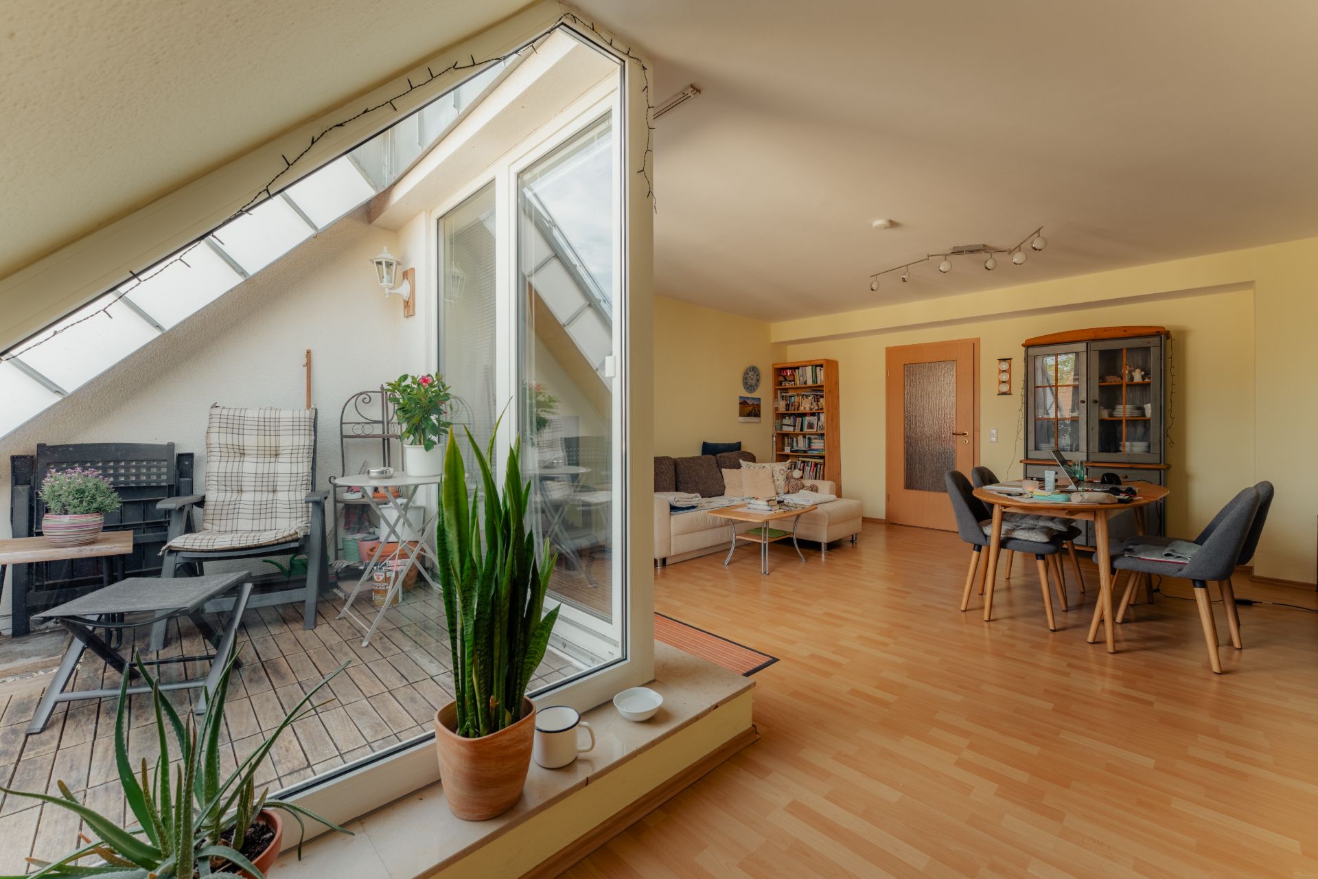 Helles Wohnzimmer mit Holzboden, Essbereich, Balkon und Pflanzen.