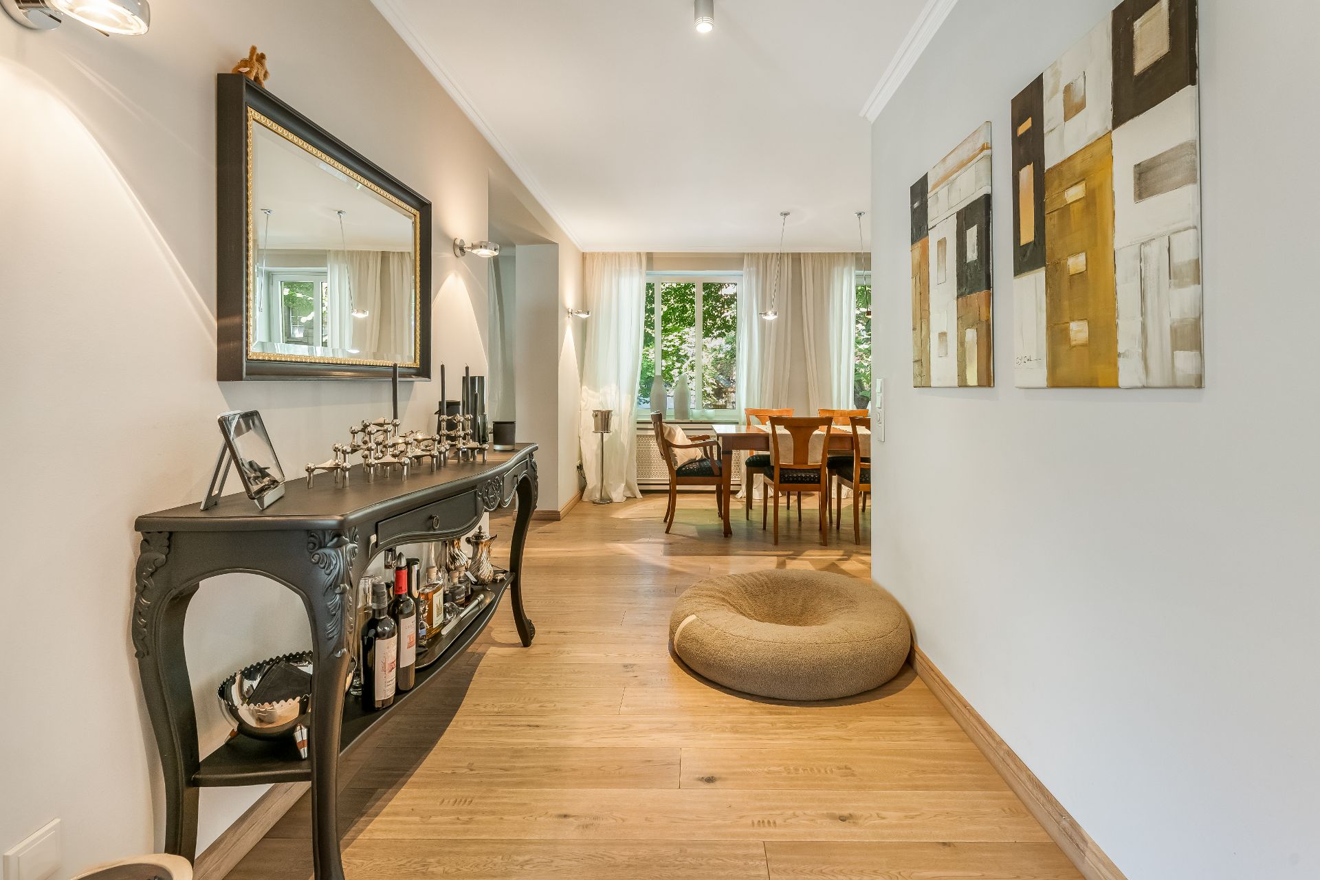 Heller Flur mit Spiegel, Sideboard, Hundebett und Blick ins Esszimmer mit Holzboden.
