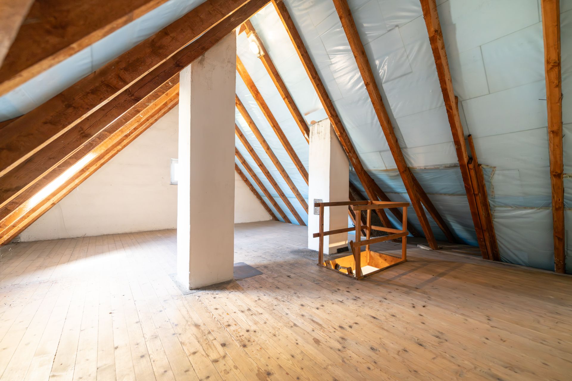 Heller Dachboden mit Holzboden, sichtbaren Balken und Treppenöffnung.
