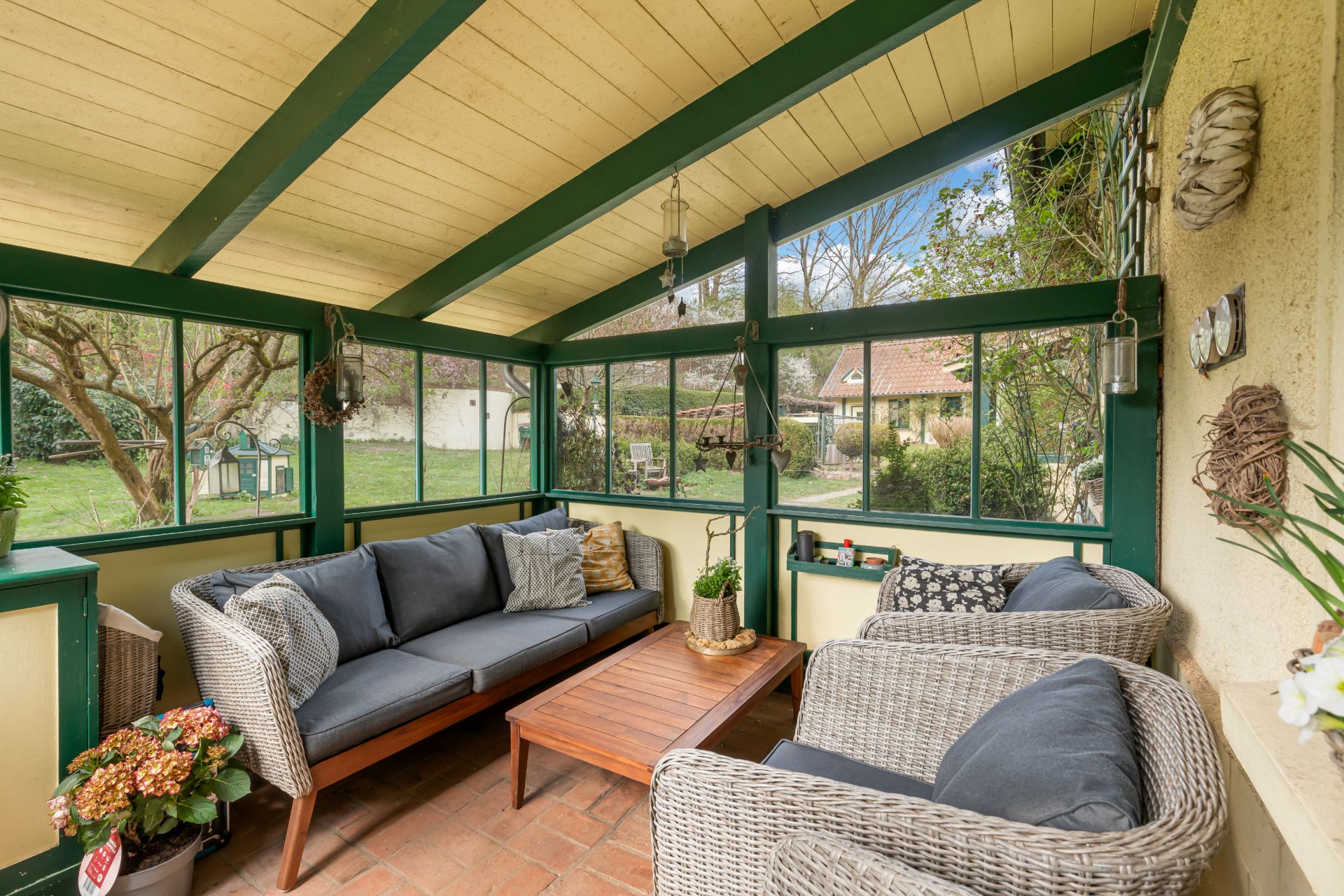 Wintergarten mit Sofa, zwei Sesseln, Couchtisch und Blick auf den Garten.