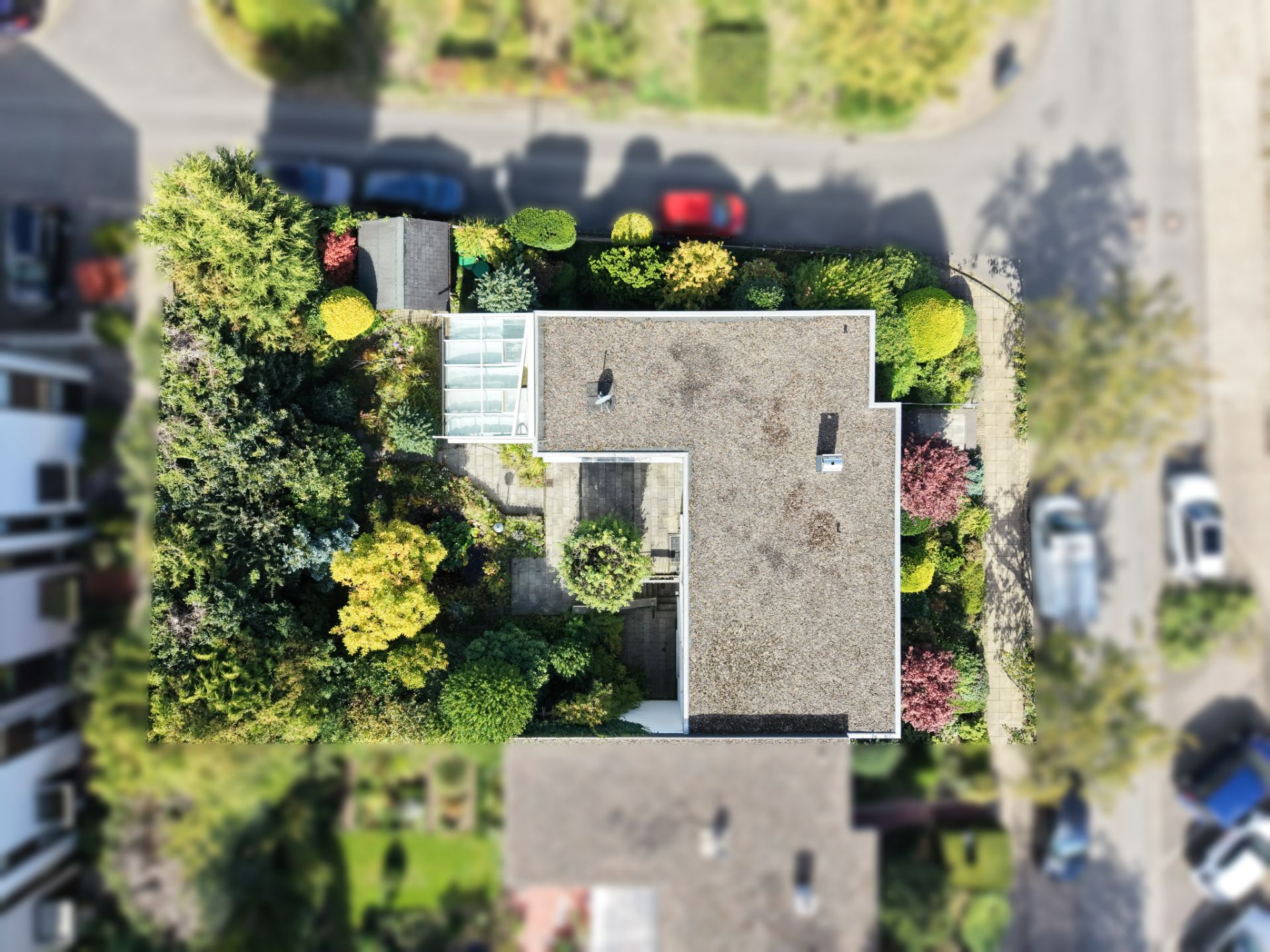 Luftaufnahme eines Hauses mit Flachdach und umliegendem Garten.