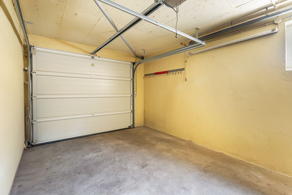 Leere Garage mit geschlossenem Garagentor und Hakenleiste an der rechten Wand.