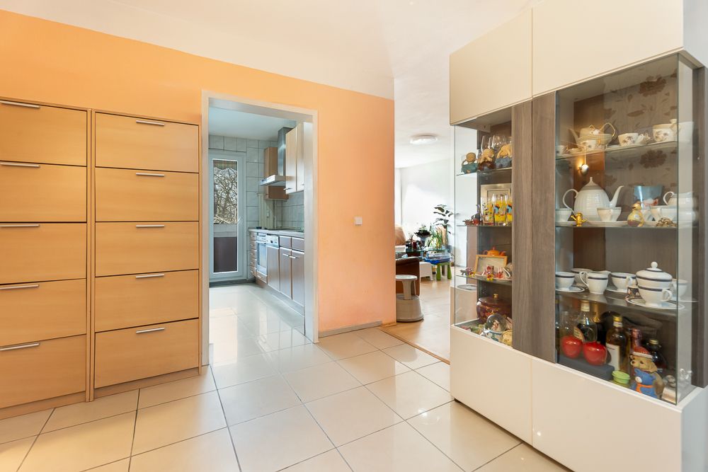 Flur mit Glasschrank und Kommoden, Blick in Küche und Wohnzimmer.