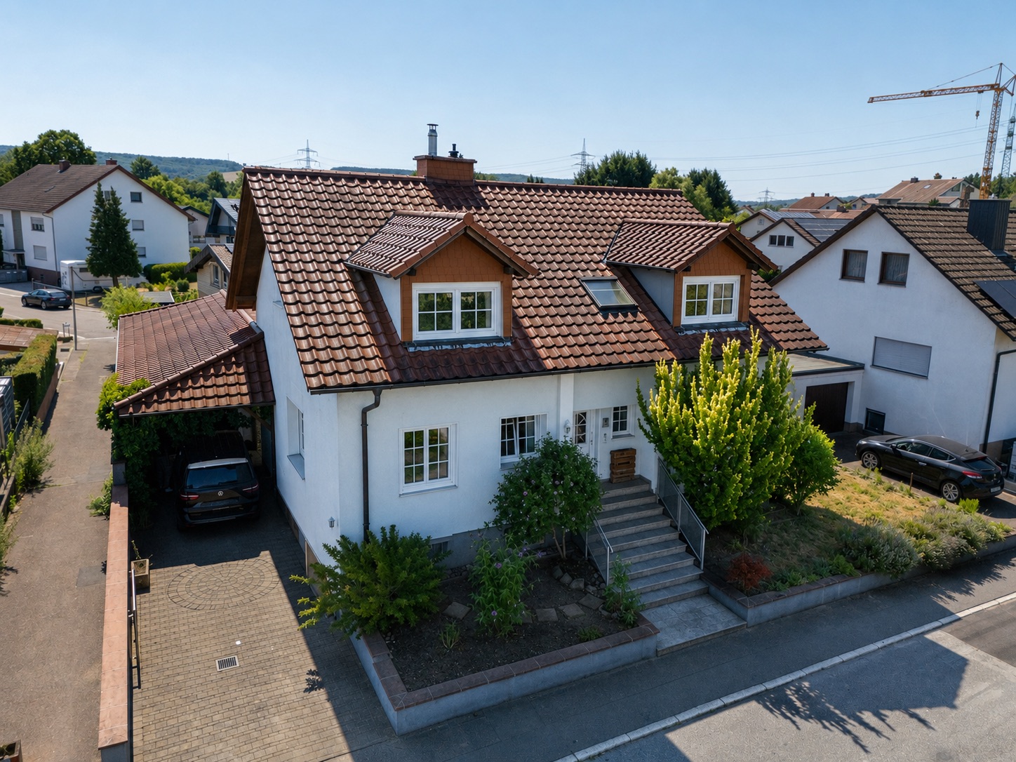 Zweistöckiges Wohnhaus mit rotem Dach, Vorgarten und Treppe zum Eingang.