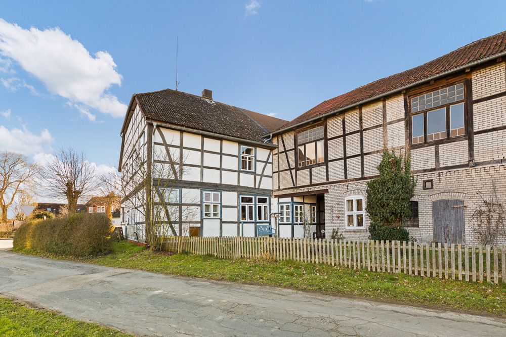 Altes Fachwerkhaus mit Holzzaun und Garten an einer ruhigen Straße.