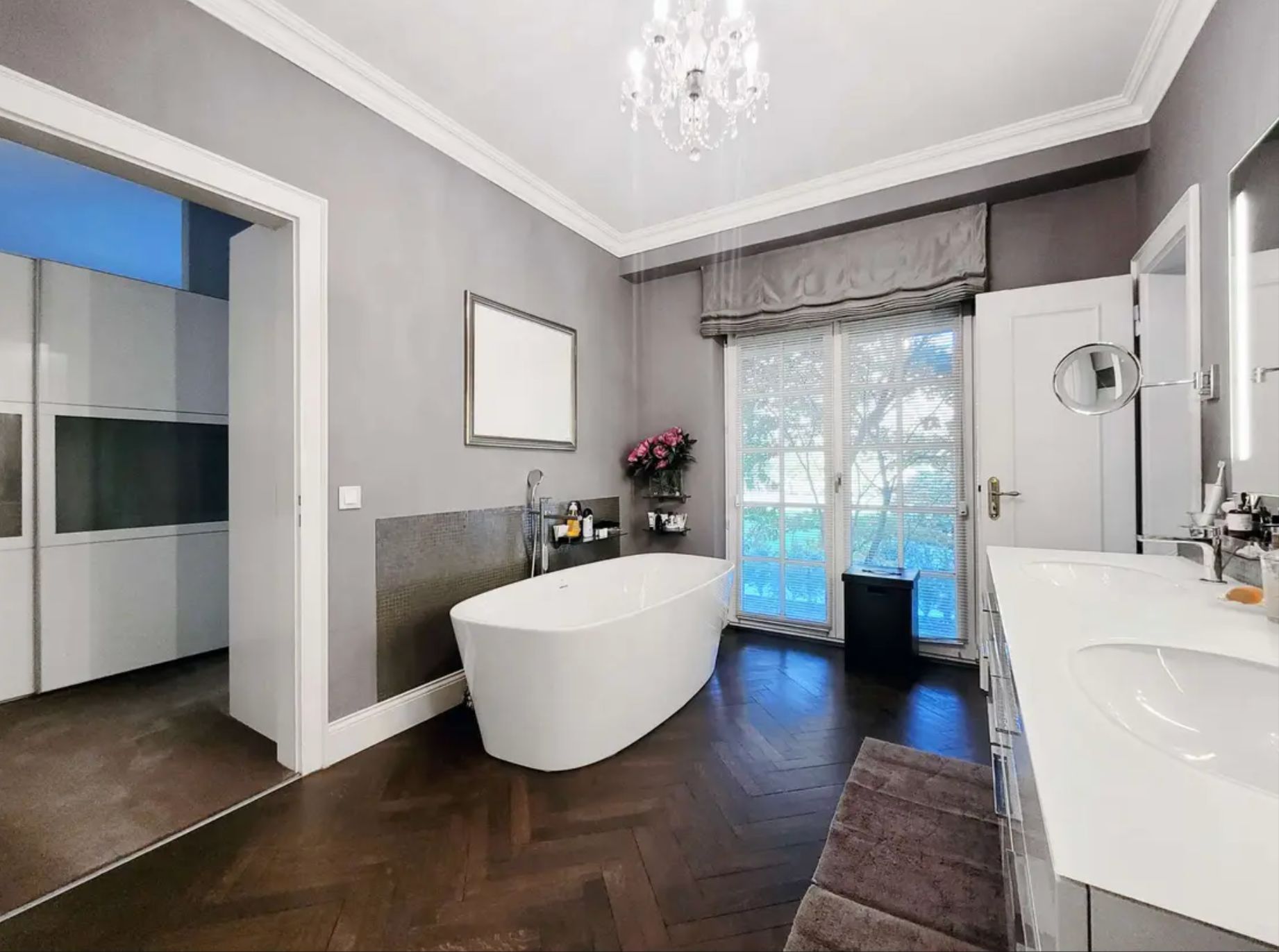 Modernes Badezimmer mit freistehender Badewanne, Doppelwaschbecken und großen Fenstern.