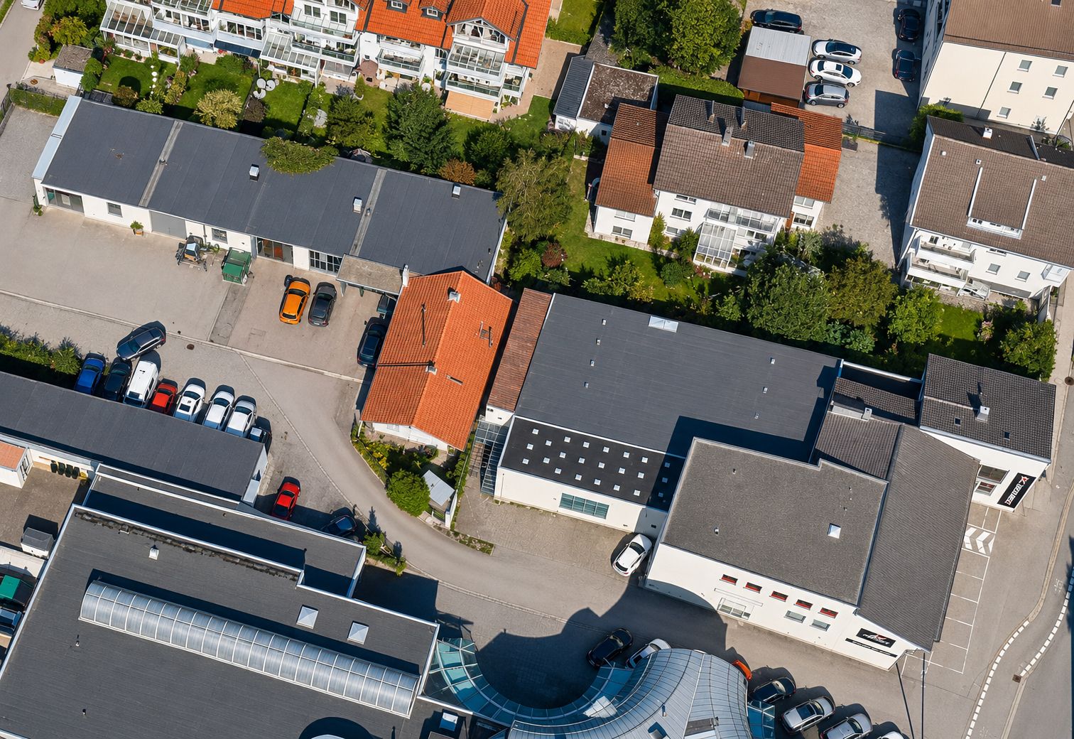 Luftaufnahme von Wohnhäusern mit Gärten und mehreren parkenden Autos auf Straßen.