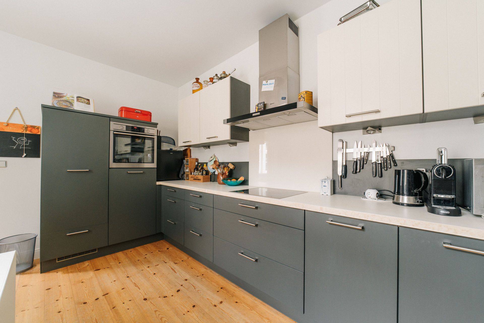 Moderne Küche mit grauen Schränken, Holzfußboden und Küchengeräten auf der Arbeitsplatte.