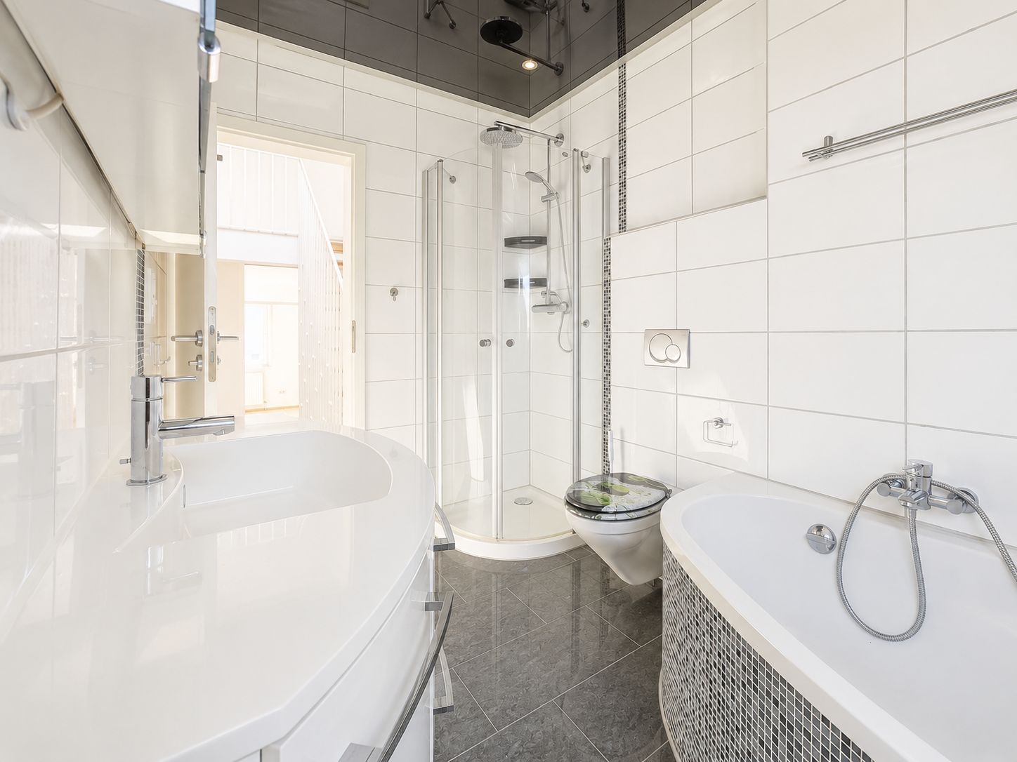 Helles Badezimmer mit Dusche, Badewanne, Waschbecken und WC, weiße Fliesen an den Wänden.