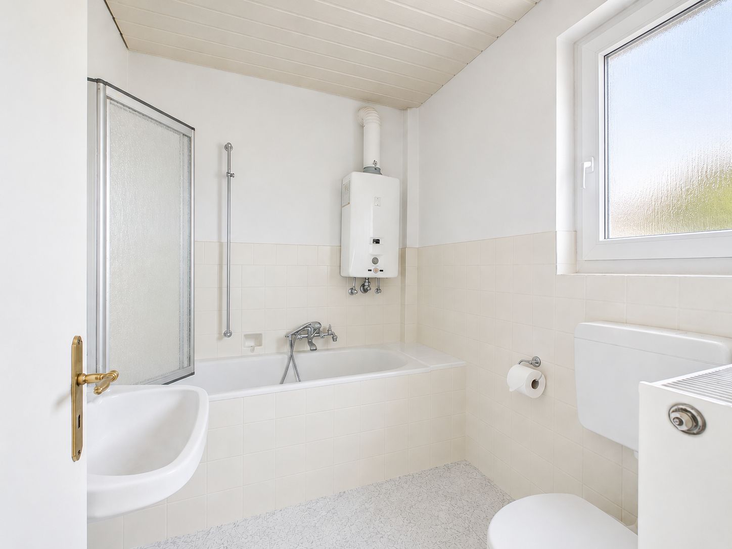 Helles Bad mit Badewanne, Waschbecken, Toilette und Fenster.