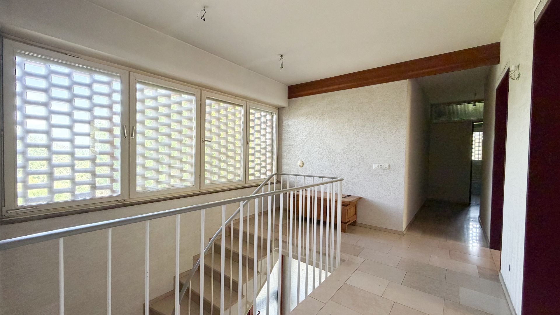 Heller Flur mit Treppe, großem Fenster und Metallgeländer in einem Wohnhaus.