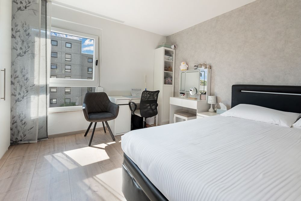 Helles Schlafzimmer mit großem Bett, zwei Schreibtischen, Stühlen und Fenster.