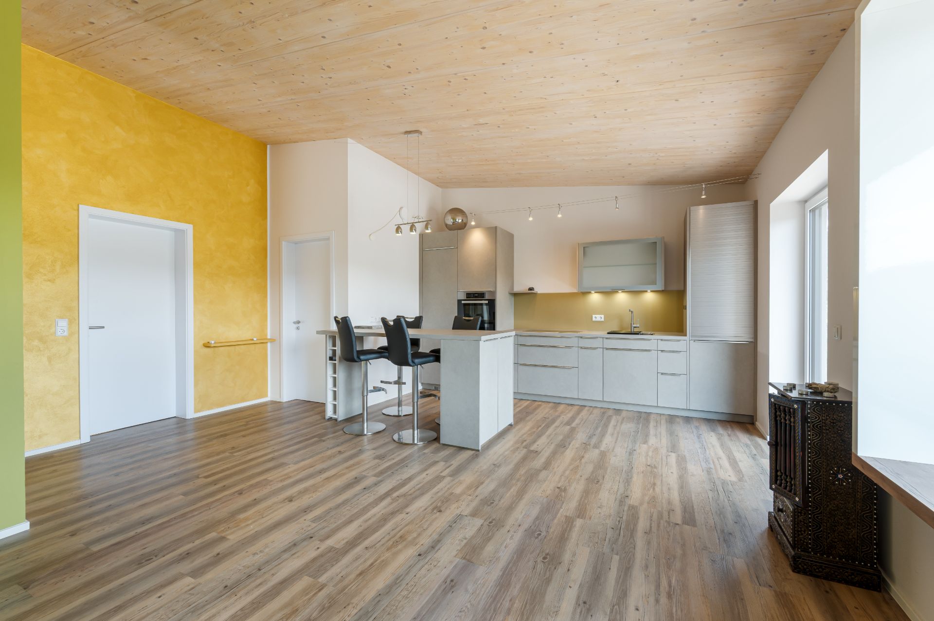 Moderne Küche mit grauen Schränken, Bartresen und Holzfußboden in offenem Wohnraum.