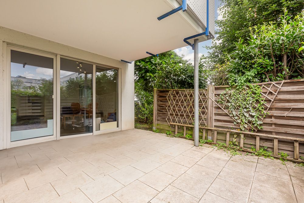 Überdachte Terrasse mit Fliesenboden, Holzsichtschutzzaun und Glas-Schiebetüren zum Wohnraum.