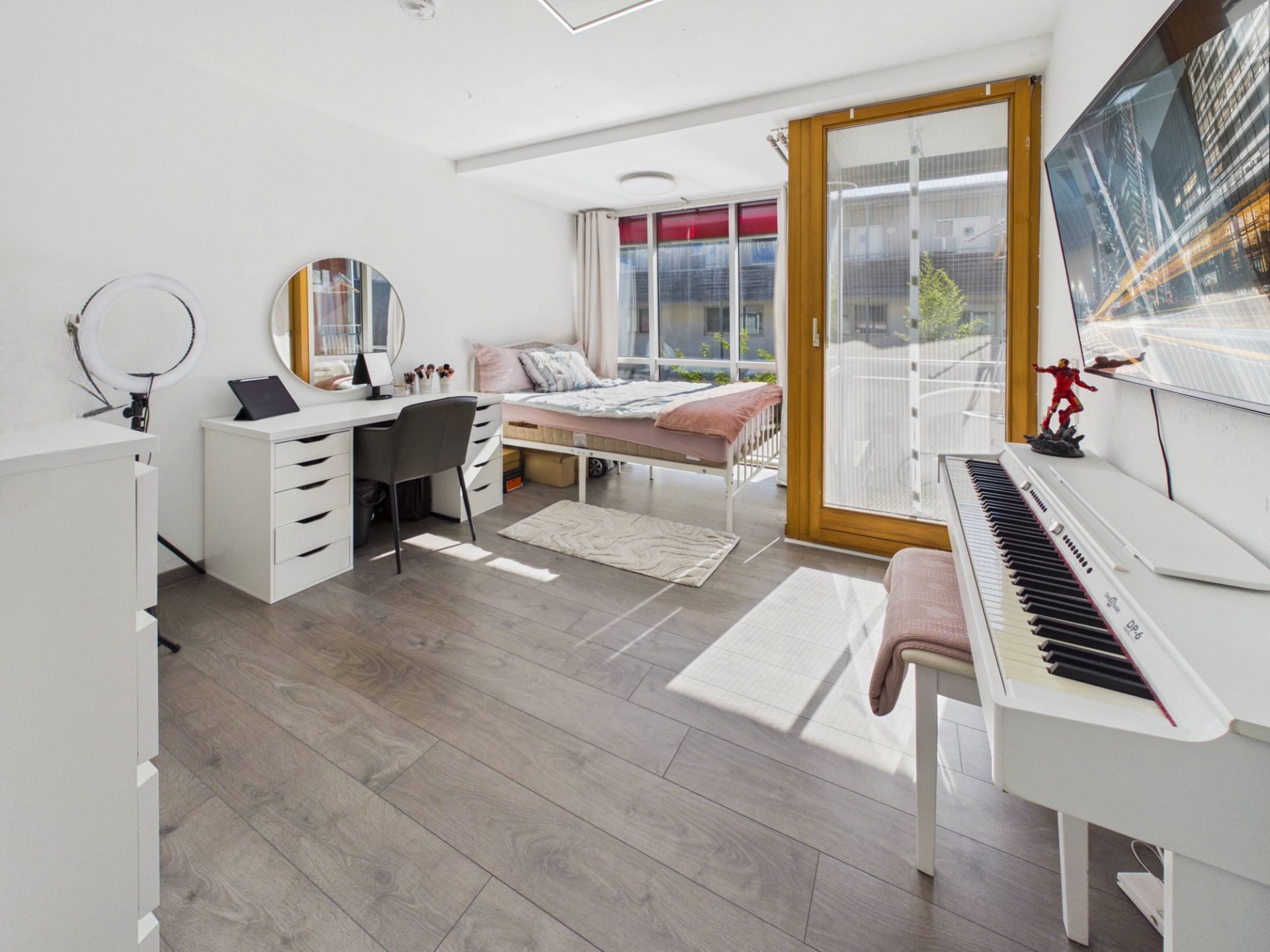 Helles Schlafzimmer mit Bett, Schreibtisch, Klavier und Zugang zum Balkon.