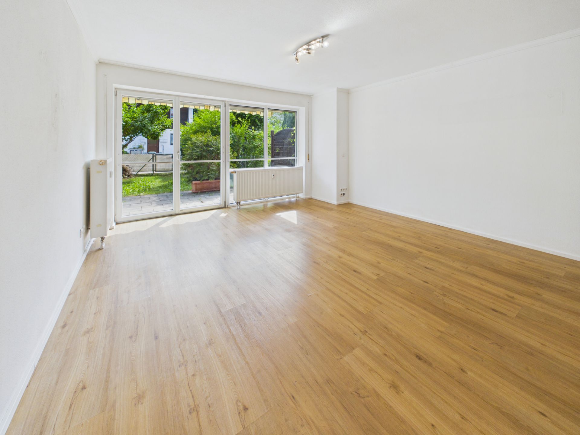 Helles Wohnzimmer mit Holzfußboden und großen Fenstern zum Garten.