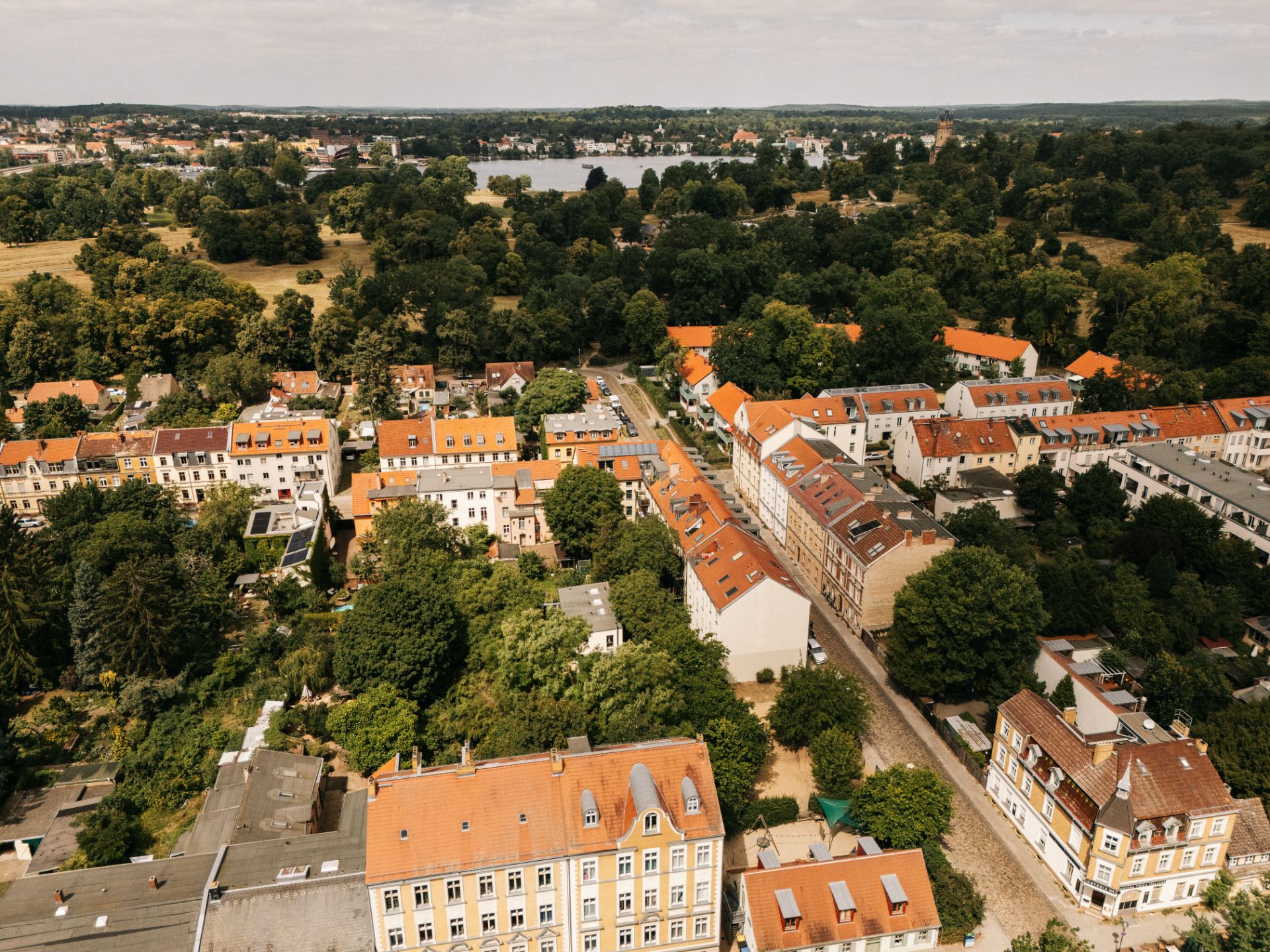Luftaufnahme von Wohnhäusern mit roten Dächern und viel Grün in einem Wohngebiet.
