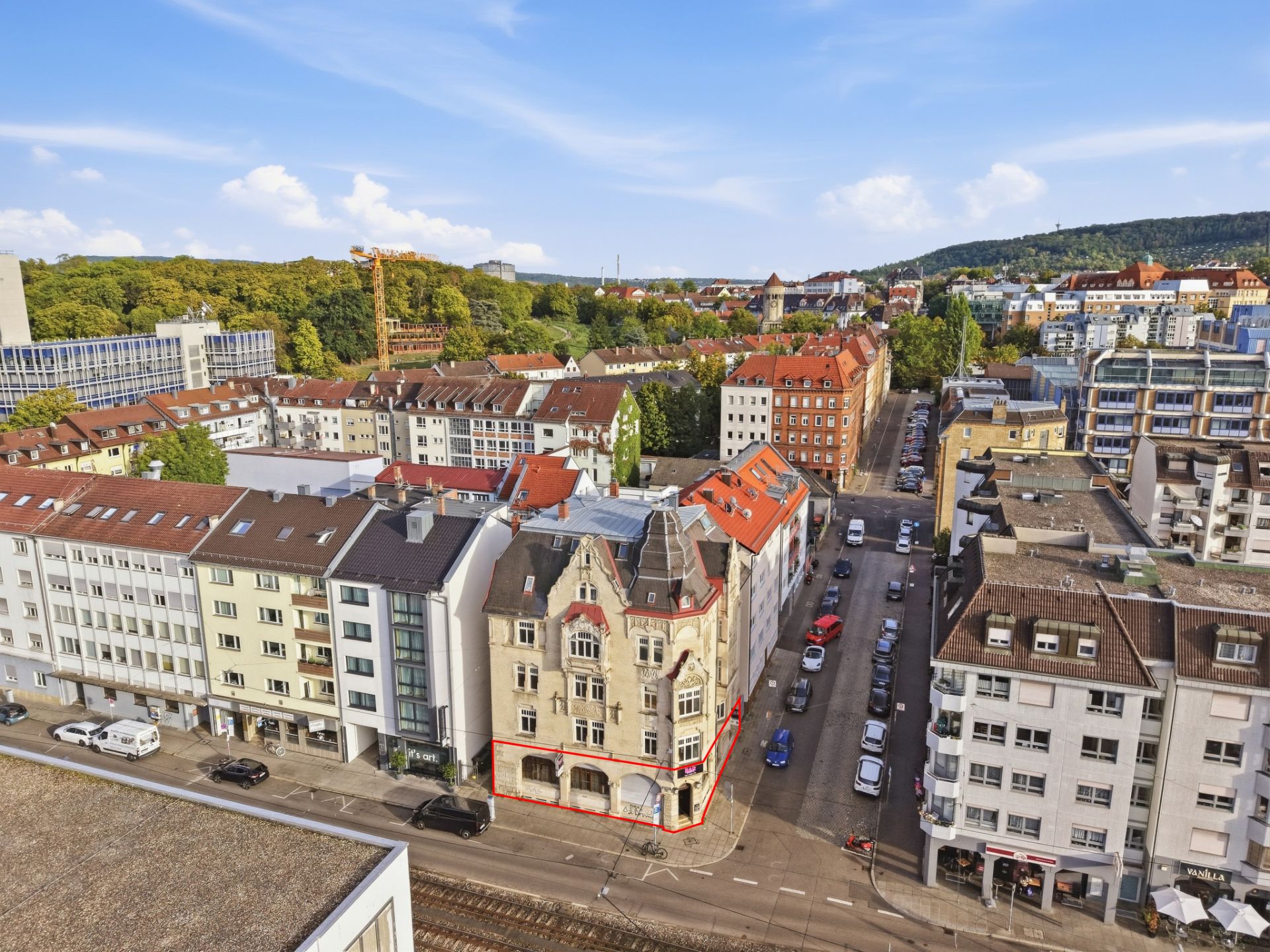 Luftaufnahme eines mehrstöckigen Wohnhauses mit markierten Erdgeschossflächen in einer Stadtstraße.