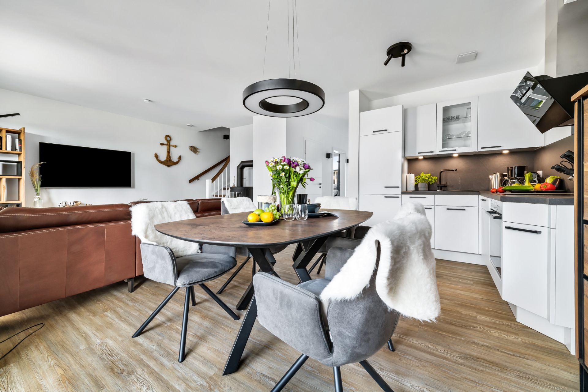 Moderne Wohnküche mit Esstisch, Stühlen, Sofa und offener Küche in heller Umgebung.