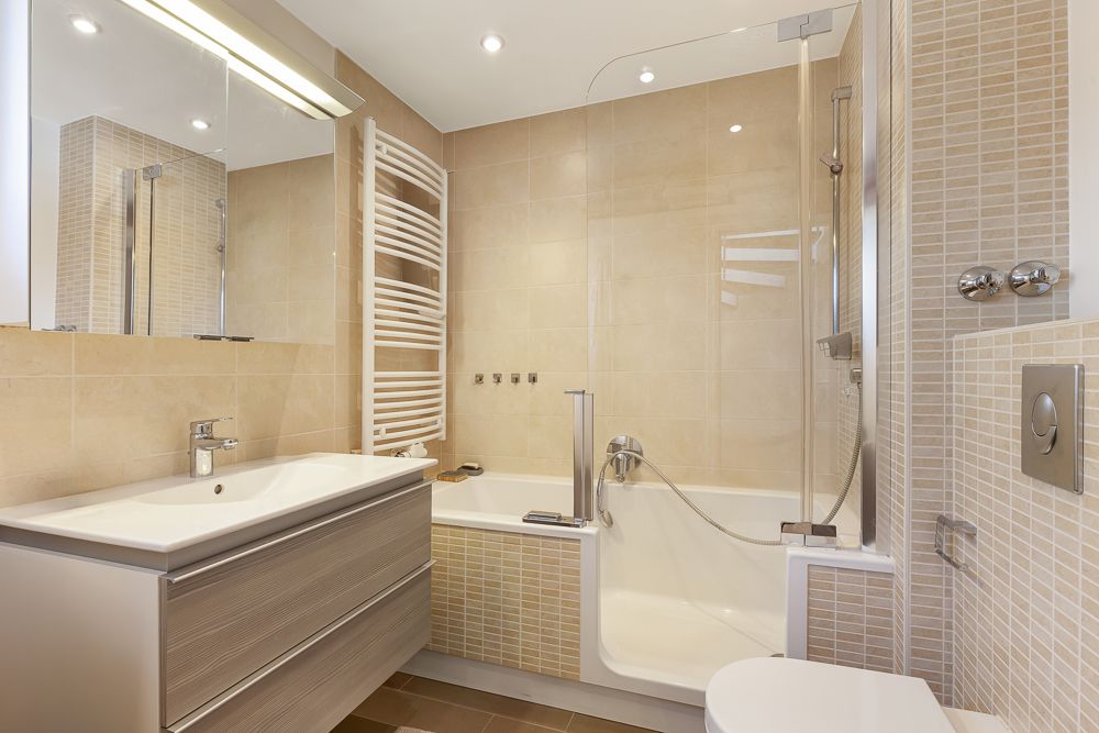 Modernes Badezimmer mit Badewanne, Waschbecken, Spiegel und Handtuchheizkörper.