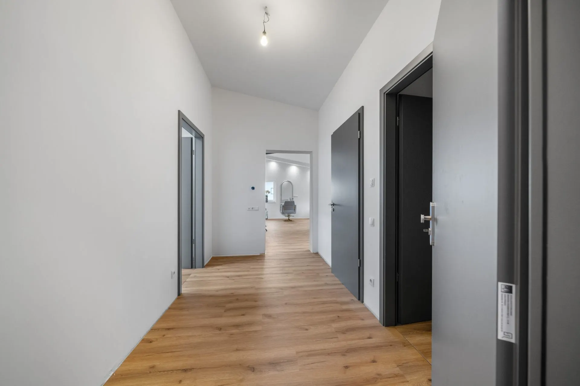 Heller Flur mit Holzboden und mehreren offenen Türen in einer Wohnung.