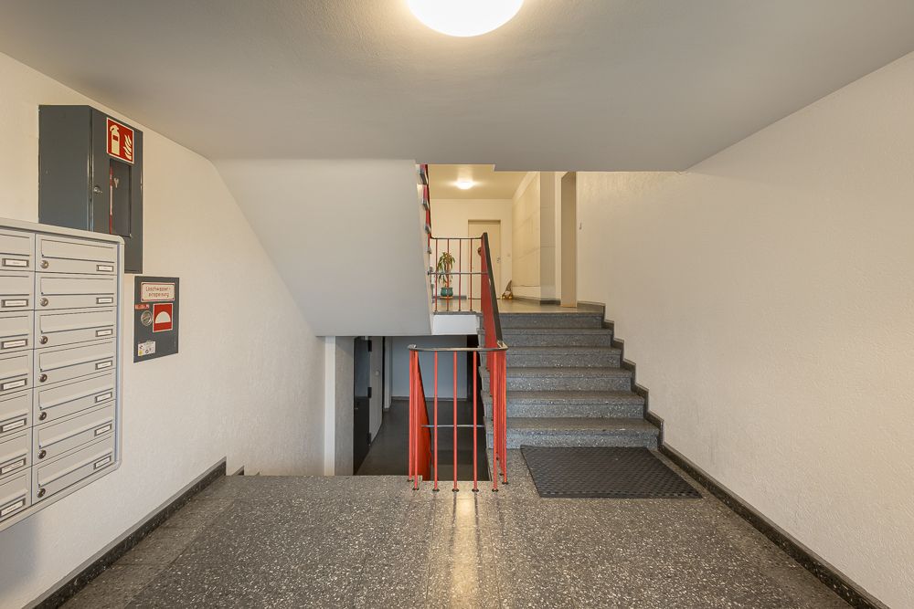 Eingangsbereich mit Briefkästen und Treppenhaus in einem Wohngebäude.