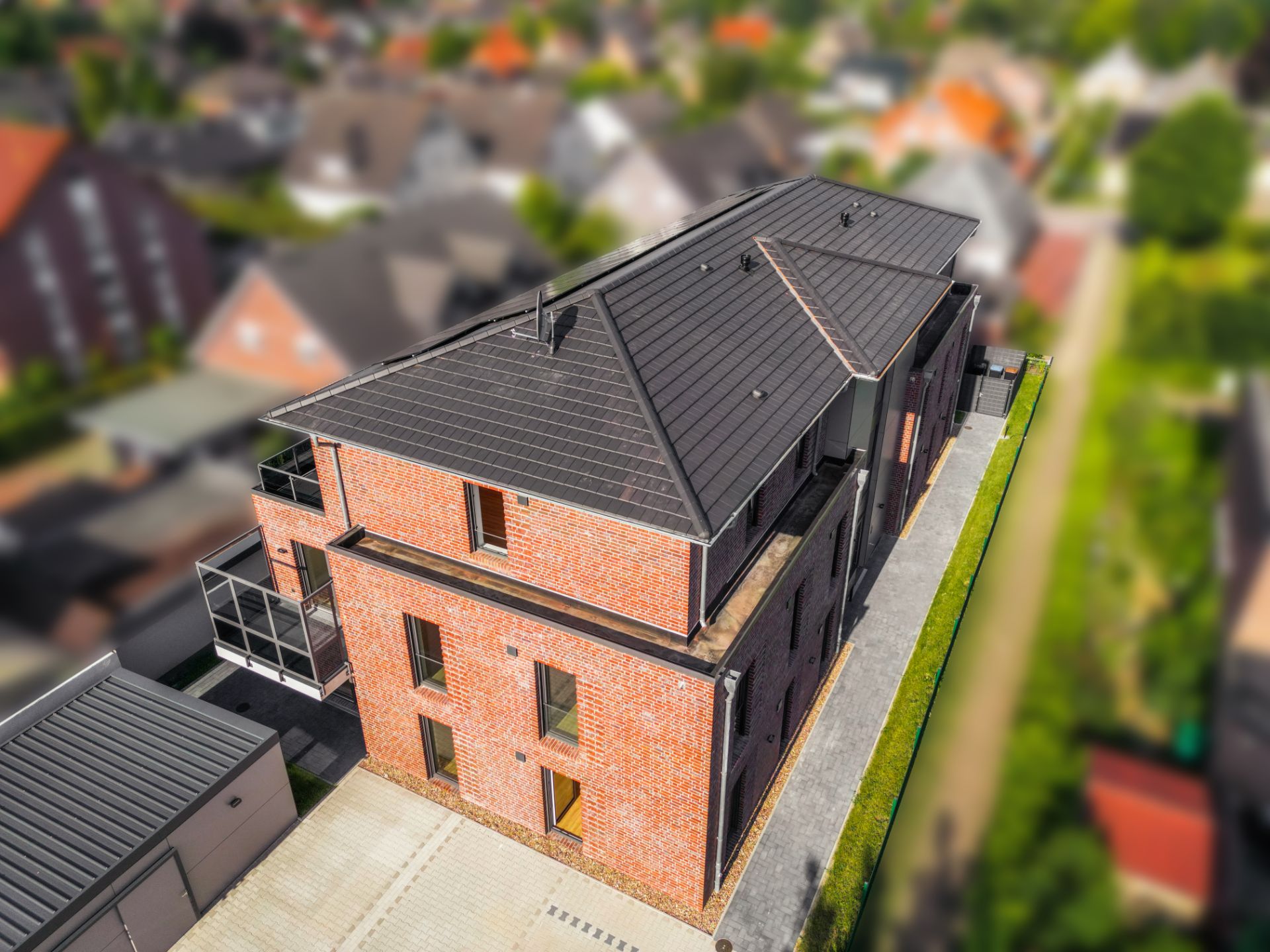 Modernes, zweistöckiges Backsteinhaus mit Flachdach und mehreren Fenstern, Vogelperspektive.