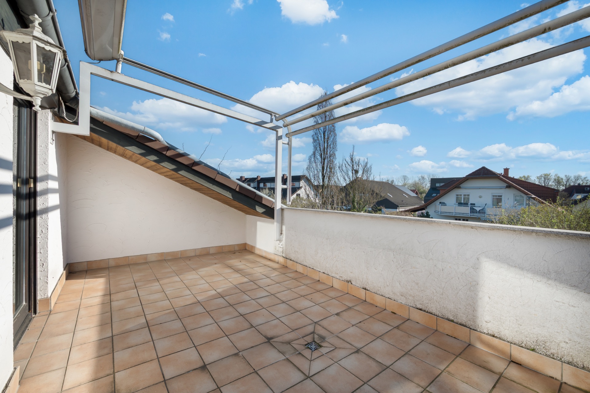 Geflieste Dachterrasse mit Überdachungsrahmen und Blick auf Nachbarhäuser.