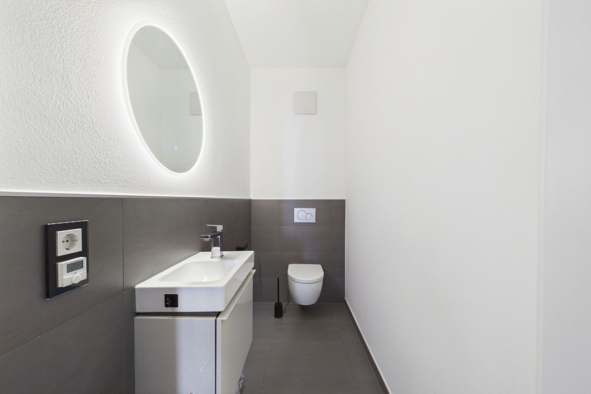 Modernes Badezimmer mit Wandspiegel, Waschbecken und wandhängender Toilette.
