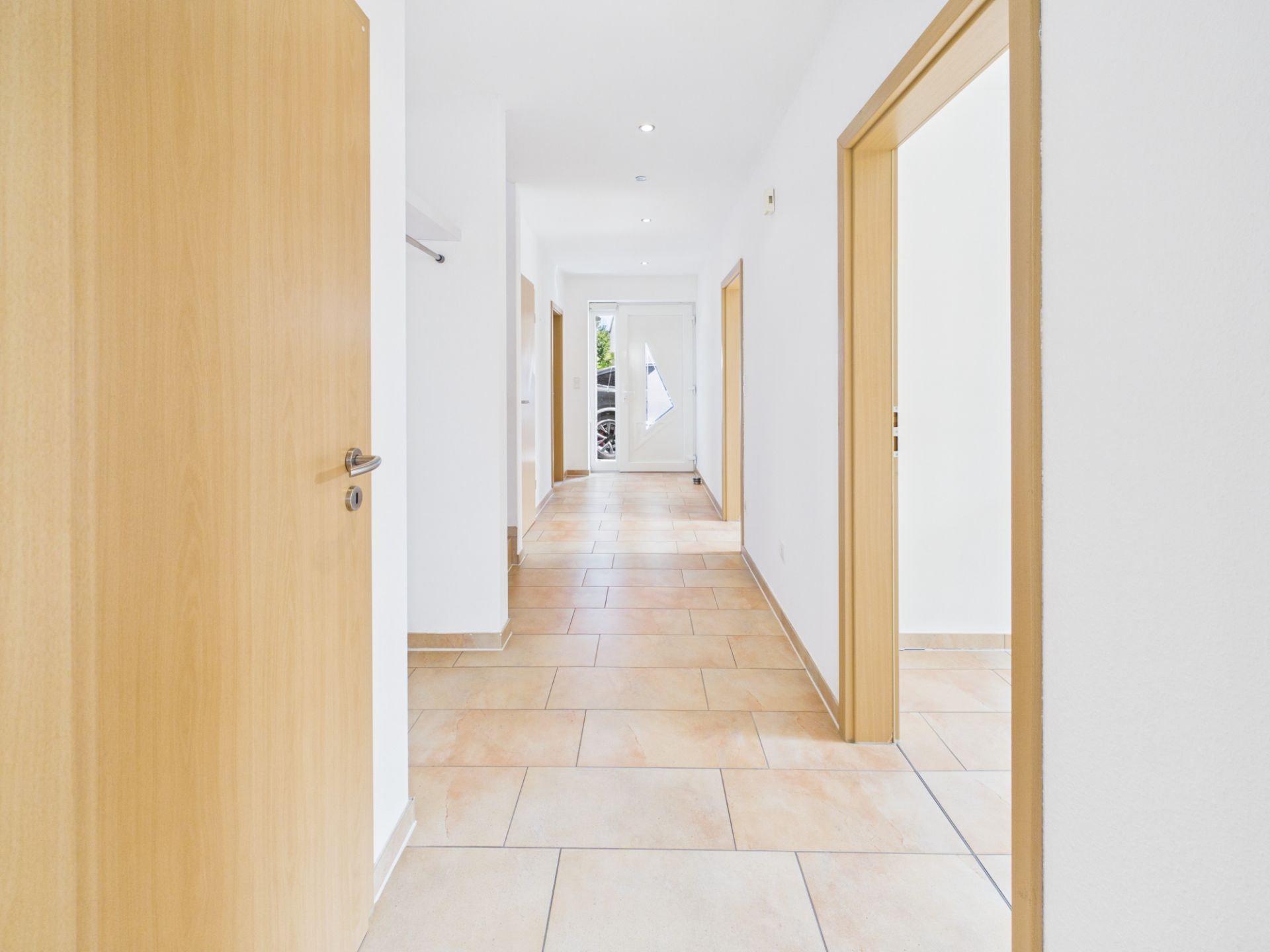 Heller Flur mit Fliesenboden und Holztüren in einem Wohnhaus.