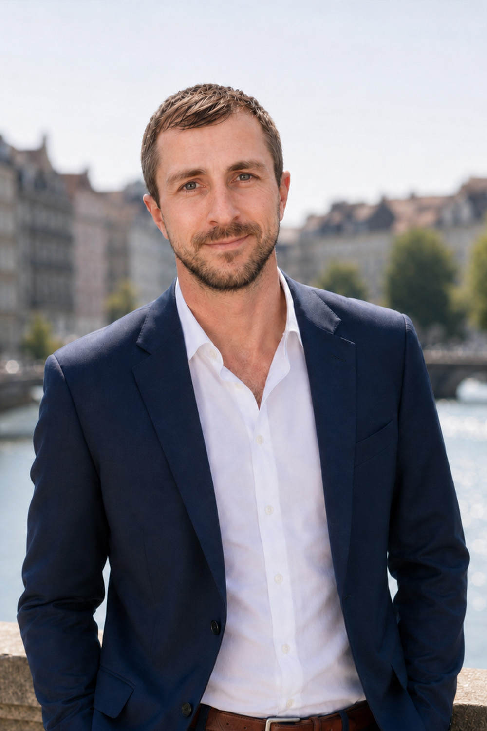 Mann im Anzug steht draußen vor Wasser und Gebäuden.