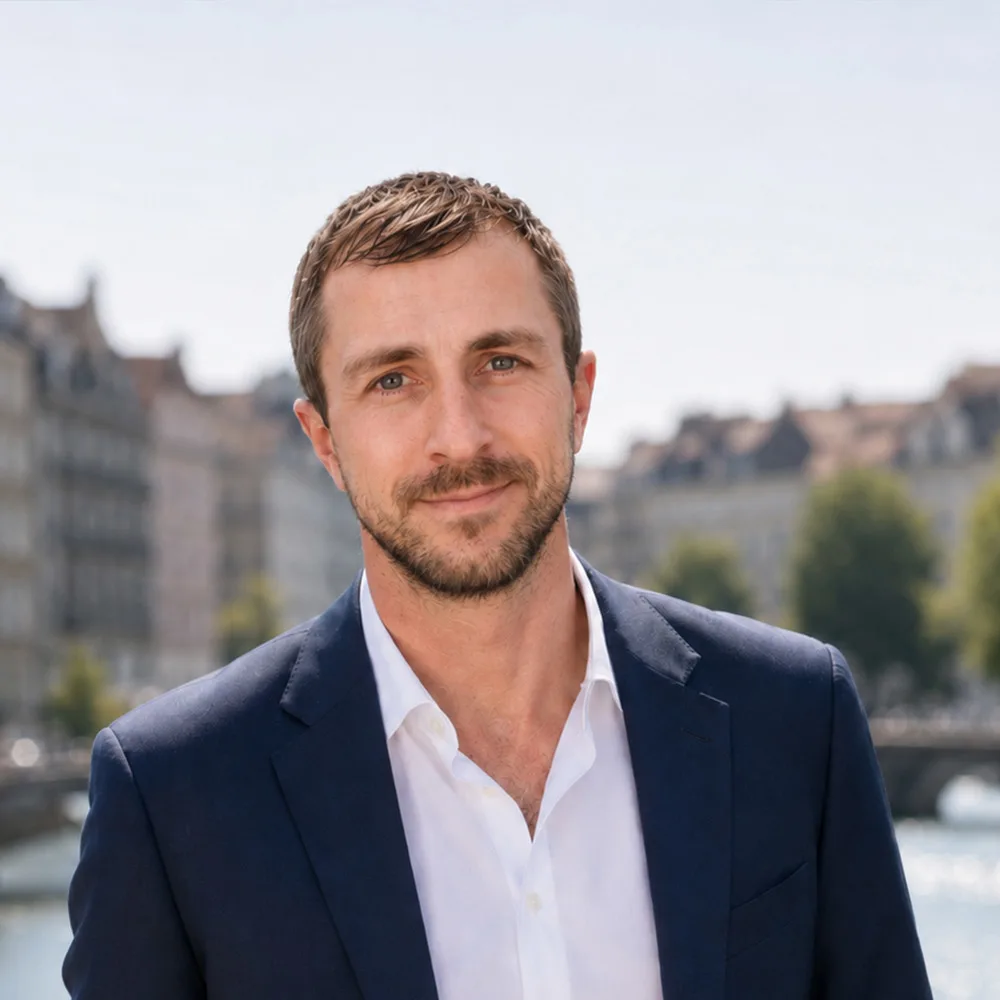 Mann im Anzug steht draußen vor Wasser und Gebäuden.